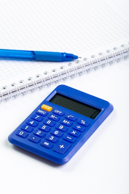 La calculatrice bleue utilise la comptabilité avec un stylo et une règle sur un bureau blanc