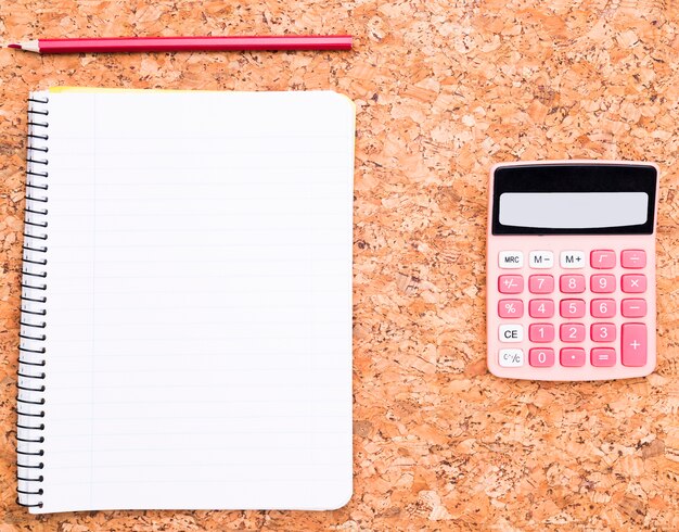 Calculatrice près de cahier et un crayon