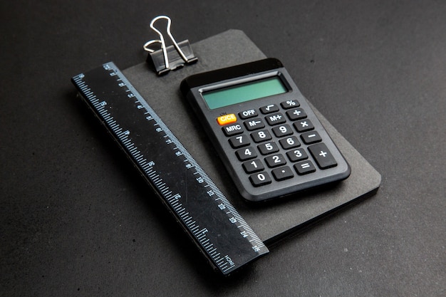 Calculatrice et règle de vue de dessous sur le bloc-notes sur une table sombre