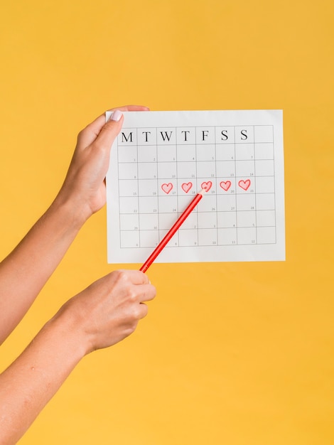 Photo gratuite calendrier de menstruations avec coeurs et un crayon