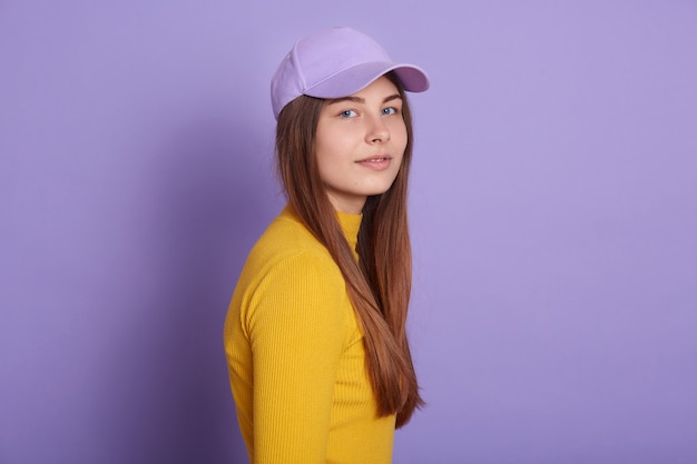 Calme dame habille tenue décontractée et casquette de baseball, posant sur le côté