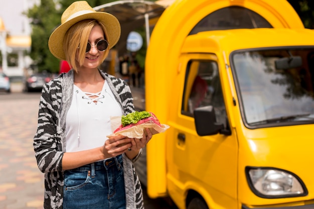 Photo gratuite camion de restauration et femme tenant un sandwich