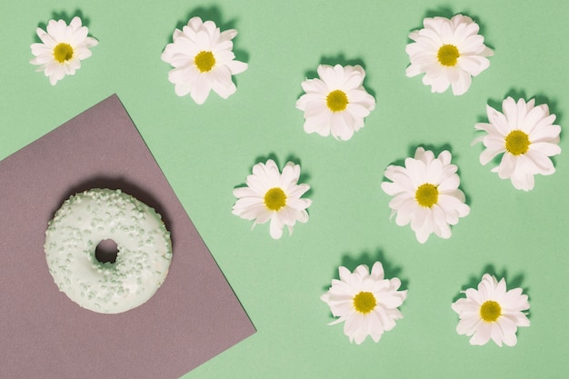 Photo gratuite camomille près de beignet et feuille de papier