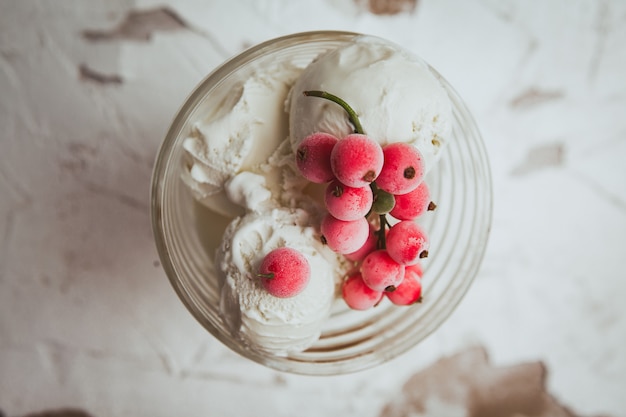 Canneberges et crème glacée dans une tasse en verre vue de dessus sur une texture blanche