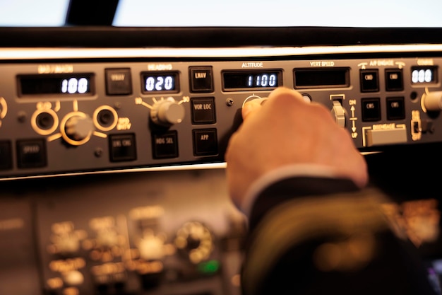 Photo gratuite le capitaine appuie sur les boutons pour fixer le niveau d'altitude sur la commande du panneau de commande, en utilisant le commutateur de navigation pour piloter un avion à réaction. radar électrique avec tableau de bord et poignée de décollage avec avion. fermer.