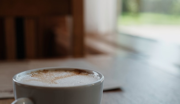 Cappuccino ou café au lait sur une table en bois. Gros plan, mise au point sélective, lumière du soleil depuis la fenêtre. Idée de pause café, pause café