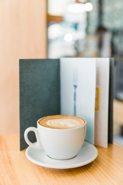 Cappuccino café avec latte d'art et menu sur table en bois