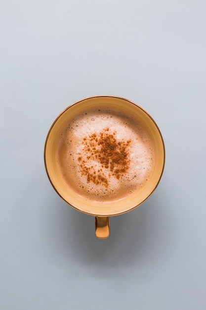 Cappuccino dans une tasse avec du chocolat en poudre sur fond blanc