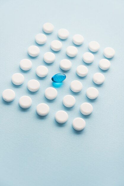 Une capsule liquide bleue dans une grille de comprimés blancs