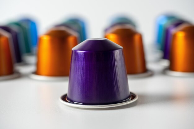 Capsules en aluminium colorées avec café moulu sur fond blanc. un violet au premier plan. capsules pour la machine à café