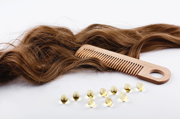 Capsules d&#39;huile avec de la vitamine E se trouvent sur les boucles de cheveux bruns