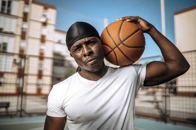 Capture d'écran peu profonde d'un joueur de basket-ball noir dans une cour extérieure