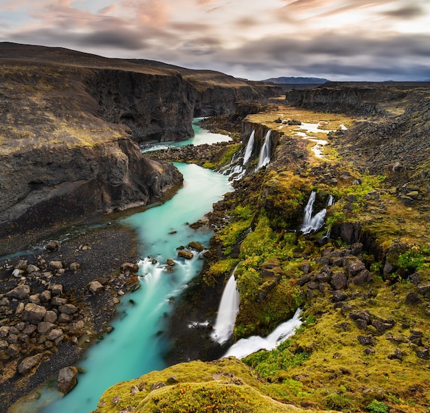 Capture en grand angle de cascades dans la région des Highlands d'Islande avec un ciel gris nuageux