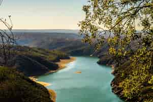 Photo gratuite capture en grand angle d'une grande rivière entourée de collines couvertes d'arbres