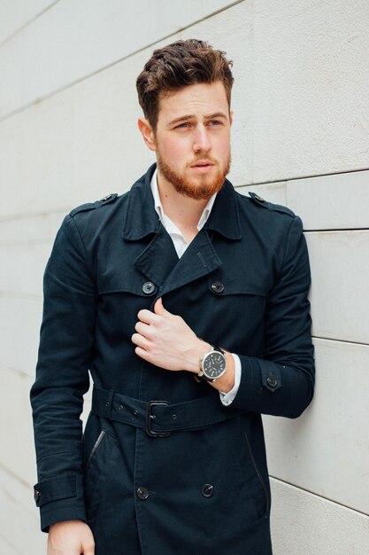 Capture verticale d'un beau mâle avec un manteau noir et une montre