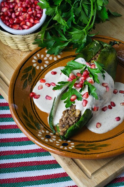 Capture verticale de Chiles en nogada dans une assiette sur une planche de bois sur la table