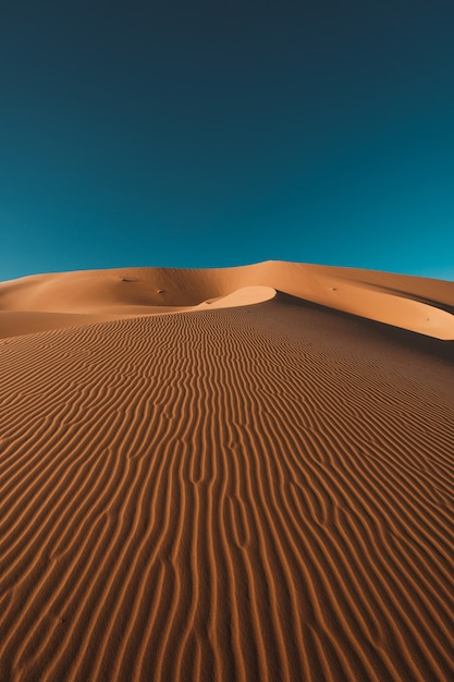 Photo gratuite capture verticale d'un désert paisible sous le ciel bleu clair capturé au maroc