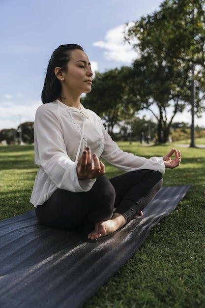 Capture verticale d'une femme hispanique faisant du yoga dans un parc