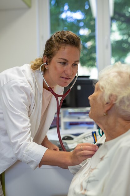 Capture verticale d'une femme médecin écoutant un rythme cardiaque âgé