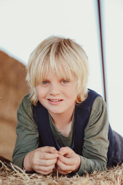 Capture verticale d'un garçon caucasien australien blond souriant allongé sur une balle de hale