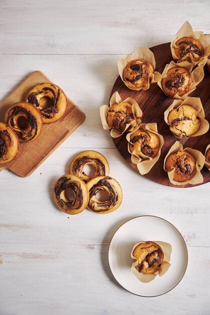 Capture verticale en grand angle de délicieux muffins au chocolat et de beignets frais sur une table blanche