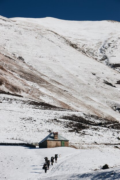 Capture verticale en grand angle de randonneurs s'approchant de la petite cabane dans les montagnes enneigées