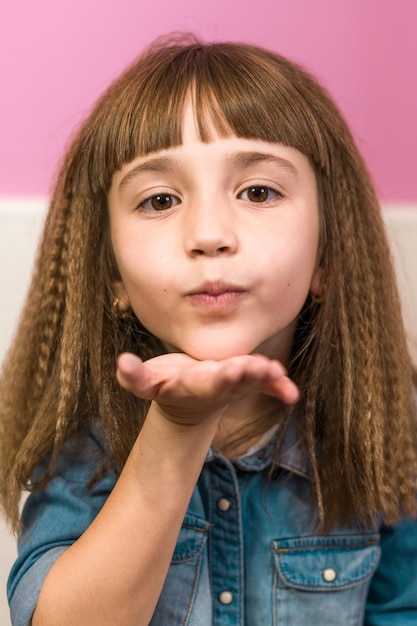 Capture verticale d'une jolie fille aux cheveux frisés et à la frange soufflant un baiser