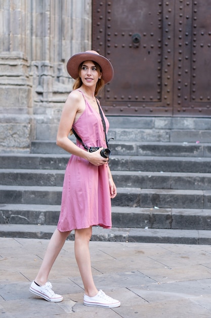 Capture verticale d'une jolie touriste blonde caucasienne portant un chapeau prenant des photos de la ville