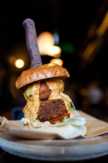 Photo gratuite capture verticale d'un savoureux hamburger sur une assiette en bois dans le restaurant