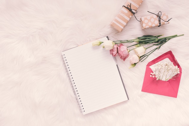 Carnet de notes avec roses, cadeaux et enveloppe sur une couverture légère