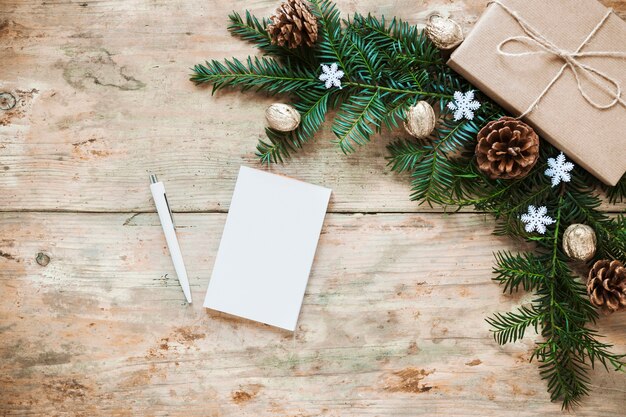 Carnet de notes un stylo près de branches de cadeaux et de conifères