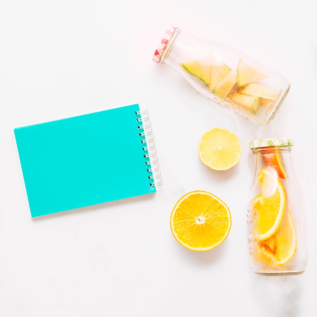 Carnet de notes turquoise citron vert avec couvercle turquoise et bouteilles en verre avec agrumes coupés