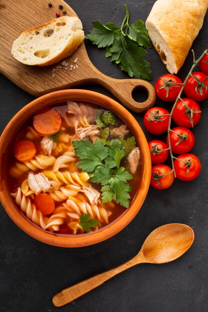 Carottes de brocoli et fusilli dans un bol avec du pain sur une planche à découper et une cuillère en bois