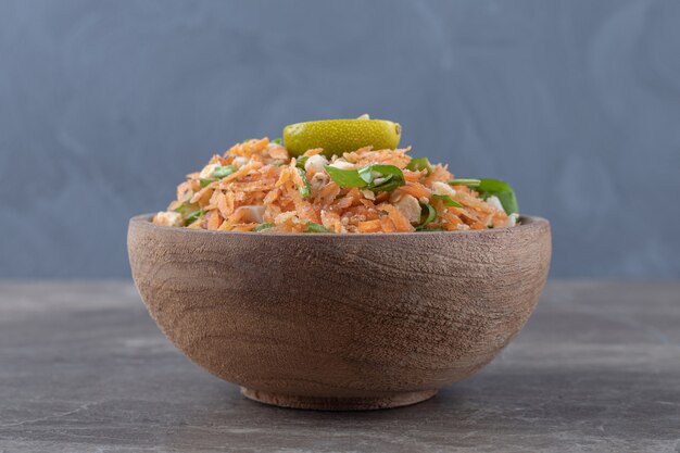 Carottes en dés et salade de légumes dans un bol en bois.