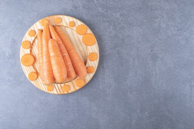 Carottes entières et tranchées dans la plaque en bois, sur fond de marbre.