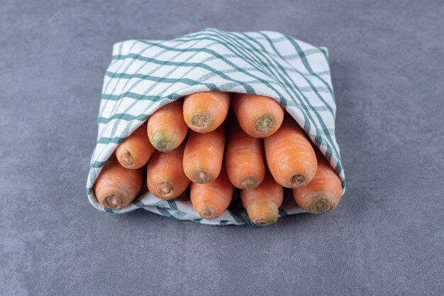 Carottes enveloppées dans une serviette, sur la surface en marbre.