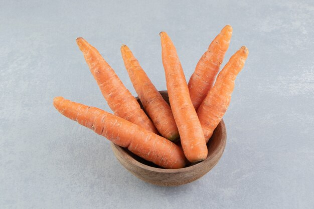 Carottes fraîches dans le bol, sur fond de marbre.