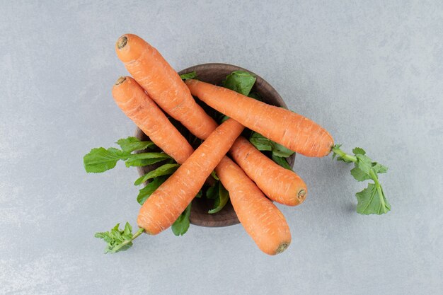 Carottes mûres dans le bol, sur le marbre.