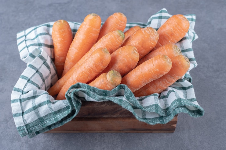 Photo gratuit carottes sur une serviette dans la boîte, sur la surface en marbre.