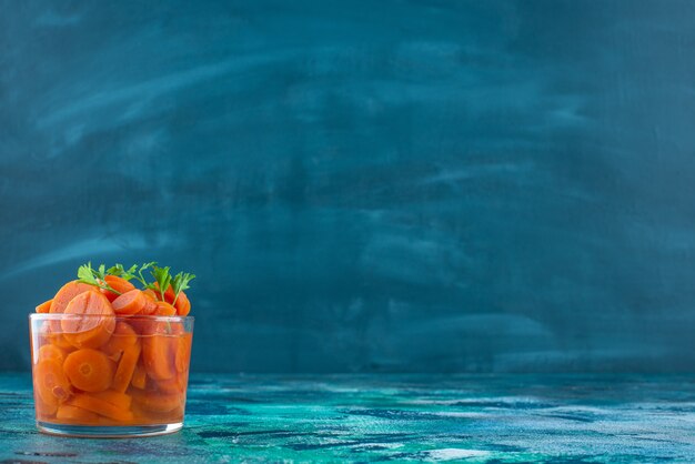 Carottes tranchées dans un verre , sur la table bleue.