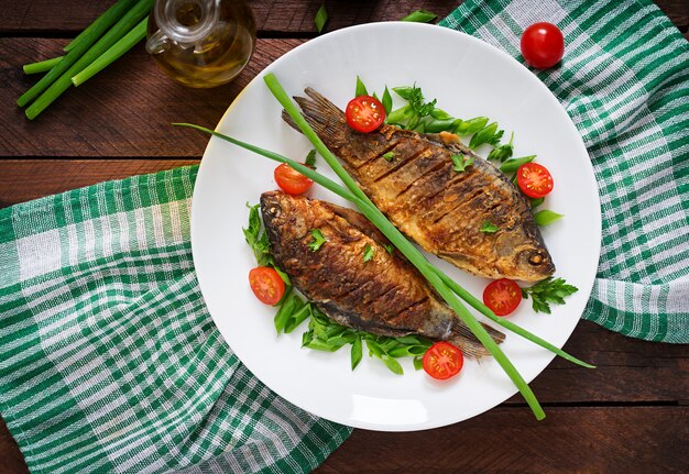 Carpe de poisson frit et salade de légumes frais sur table en bois. Mise à plat. Vue de dessus