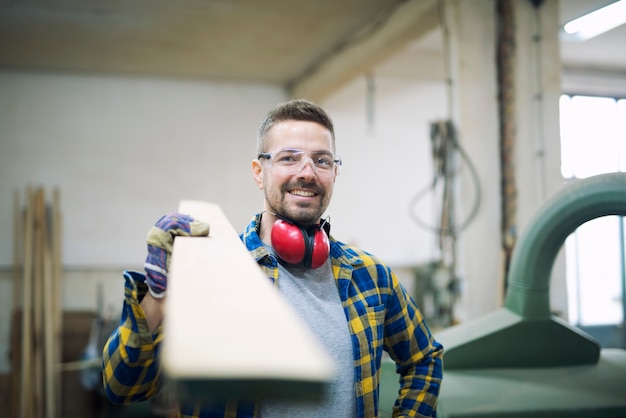 Photo gratuite carpenter holding planche en atelier de menuiserie