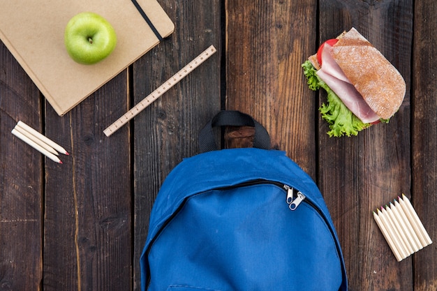 Cartable, sandwich et papeterie sur table