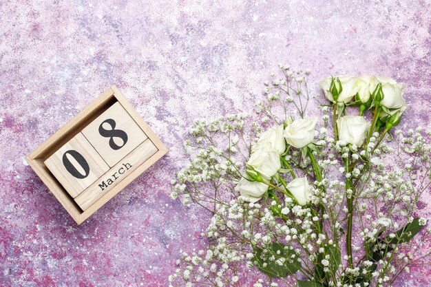 Carte de la journée de la femme du 8 mars avec des fleurs blanches, des bonbons et une tasse de thé