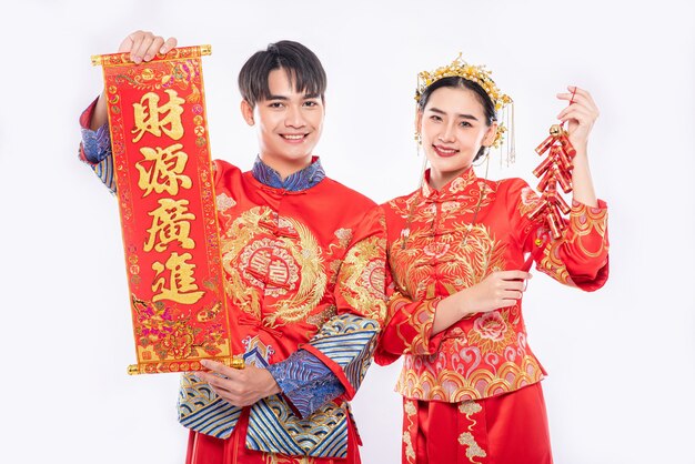 La carte de voeux chinoise et le pétard sont utilisés par l'homme et la femme portant un costume Cheongsam pour célébrer le nouvel an chinois