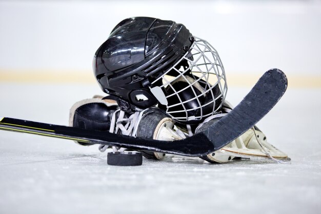 Casque de hockey, rondelle, bâton et patins sur la patinoire de hockey