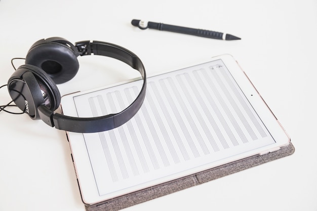 Casque de musique; stylet et tablette numérique graphique avec note de musique à l&#39;écran sur fond blanc