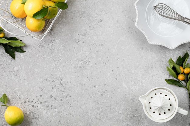 Une casserole en céramique blanche et des citrons frais sur une table en pierre blanche