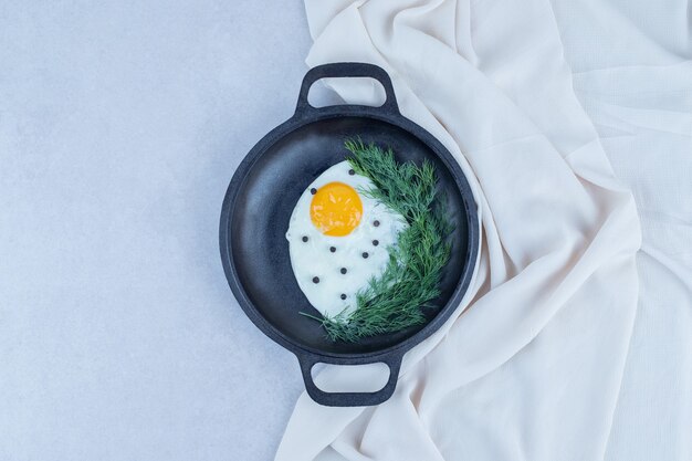 Une casserole d'omelette avec du poivre et des verts.