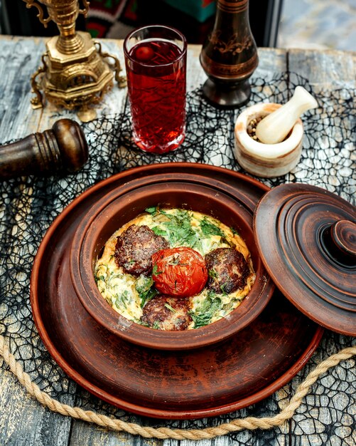 Une casserole de poterie avec des boulettes de viande cuites à l'oeuf aux épinards